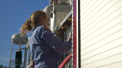 Female-firefighter-preps-gear-on-a-fire-truck-to-be-ready-for-emergency-response-and-firefighting