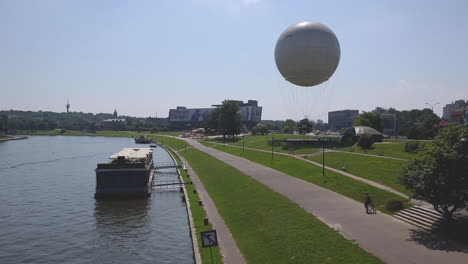 Vistula-river-with-Hotel-Forum-and-hot-air-balloon-in-background,-Cracow,-Poland
