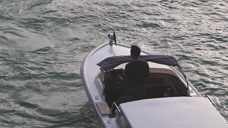 Mann-Fährt-Luxus-Motorboot-Auf-Den-Kanälen-Von-Venedig,-Das-Im-Winter-Das-Sonnenlicht-Reflektiert