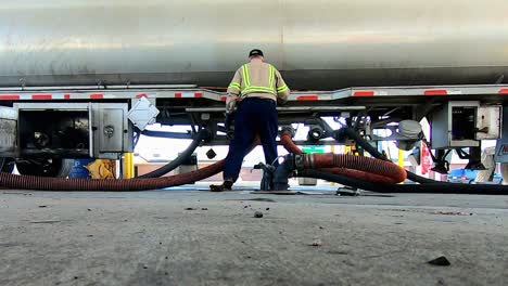 High-definition-low-angle-footage-of-a-driver-unloading-fuel-using-hoses-from-a-tractor-trailer-fuel-tanker