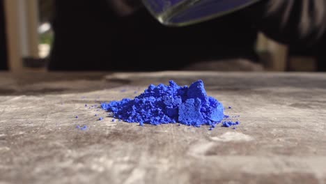 Artist-prepering-blue-powder-pigment-on-table-in-workshop,-closeup