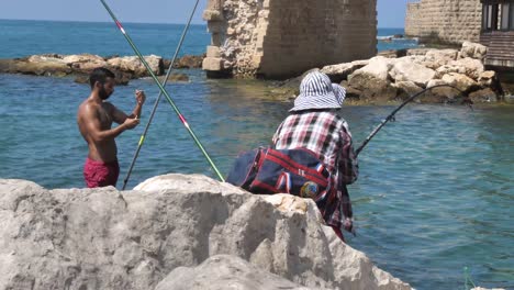 Fishermen-in-Acre-Northern-Israel-on-old-fortification-background