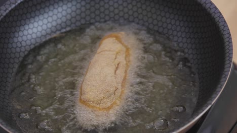 oil-bubbles-while-frying-chicken-breast-in-a-cooking-black-pot