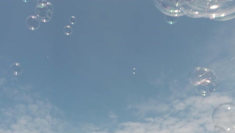 Many,-clear-soap-bubbles-against-bluesky-with-small-clouds