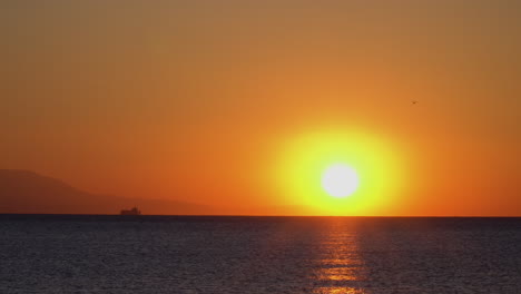 Wunderschöne-Statische-Aufnahme-Eines-Sonnenaufgangs-Mit-Boot-Und-Bergen-Am-Horizont