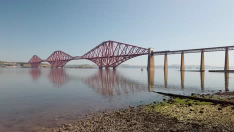 Forth-Railway-Bridge-with-a-train-passing-over-it-on-its-way-to-Edinburgh-on-a-hot-calm-day