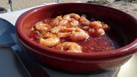 Traditional-Spanish-Gambas-pil-pil-on-the-beach-in-sunny-weather-with-a-sea-view-in-Marbella,-Spain