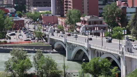 Tráfico-En-Un-Puente-Fluvial-Urbano,-En-El-Centro-De-La-Ciudad-Al-Fondo