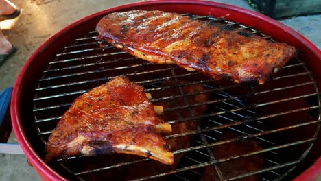 A-close-up-shot-of-a-man-pulling-ribs-off-the-smoker-with-tongs-after-pulling-up-the-lid