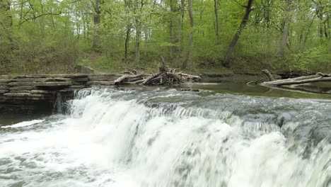 Eine-Schräge-Vorwärtsbewegung-Zu-Einem-Kleinen-Waldflusswasserfall-Mit-Einem-Otterdamm-Im-Fluss