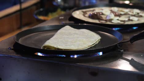 Close-shot-of-a-folded-pancake-in-a-pan-in-top-of-a-fire