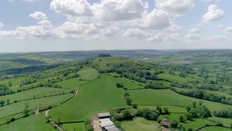 Sideways-aerial-of-a-solitary-hill-in-a-vast-countryside-landscape-in-late-spring