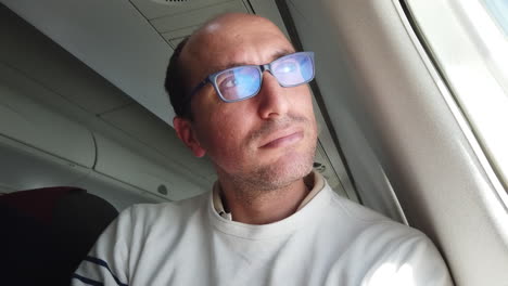 Ein-Ernster-Mann-Mit-Brille-Schaut-Aus-Einem-Flugzeugfenster