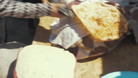 Afghan-woman-takes-baked-traditional-bread-out-of-Tandoor-oven-refugee-camp