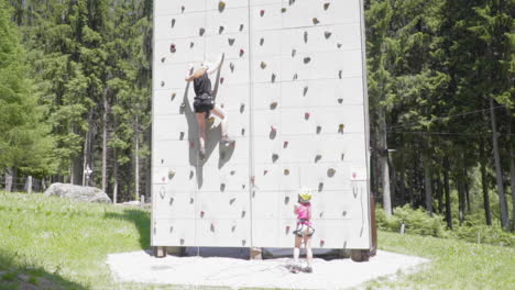 Mom-and-daughter-climb-a-training-wall,-slow-motion