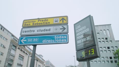 Traffic-signs-by-digital-clock-and-thermometer,-foggy-morning-in-Seville,-Spain