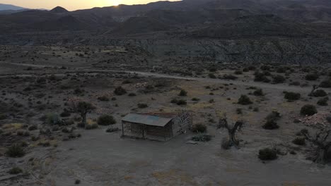 Log-cabin-in-Tabernas-desert-at-sunset-with-drone,-Almeria,-Spain
