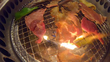 Tongs-flipping-grilled-meat-on-yakiniku-all-you-can-eat-Japanese-barbecue