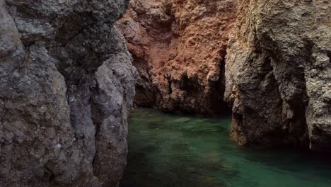 Small-pool-of-green-sea-water-in-a-hidden-limestone-cave,-Portugal