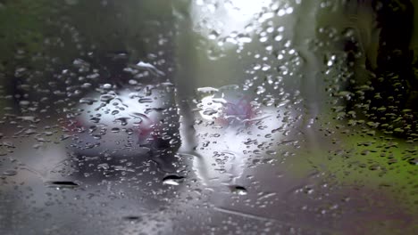 Eine-Regenbedeckte-Windschutzscheibe,-Während-Im-Hintergrund-Unscharfe-Autos-Vorbeifahren