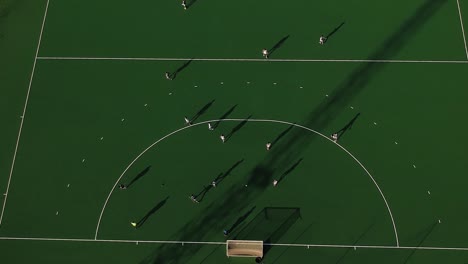 An-overhead-pan-down-drone-shot-of-a-field-hockey-game-under-sunny-conditions