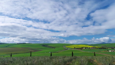 TimeLapse---Clouds-moving-over-green-hills-of-countryside,-shot-from-vantage-point-over-olive-grove