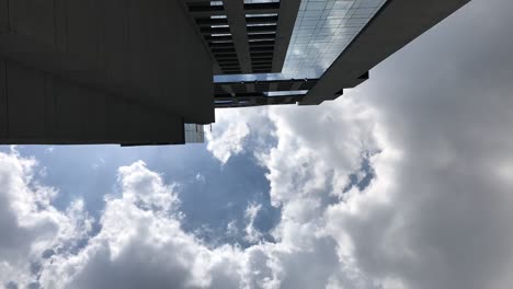 timelapse-of-clouds-moving-past-a-skyscraper,-looking-up-the-side-of-a-sky-scraper-building