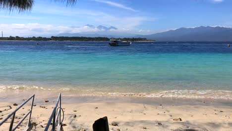 Boat-sailing-away-to-Lombok-with-blue-water-and-mountain-view-in-Gili-trawangan,-Bali,-Indonesia