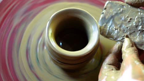 Dirty-hands-making-pottery-on-wheel-spinning-top-view-close-up