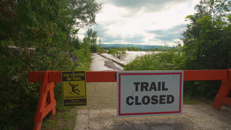 Waves-crashing-into-a-bulwark-behind-a-sign-that-reads-"Trail-Closed
