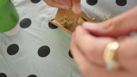 Hands-crushing-up-cannabis-to-make-a-joint-on-a-picnic-table