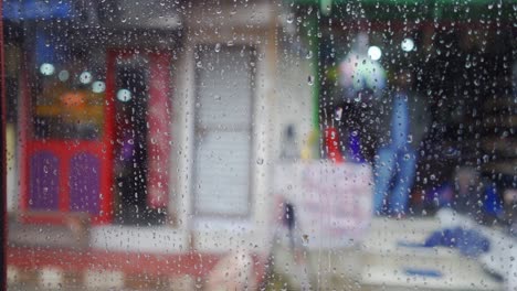 View-from-inside-car-window-on-rainy-day,-blurred-faces-of-people-and-places,-slow-motion-raindrops-on-glass