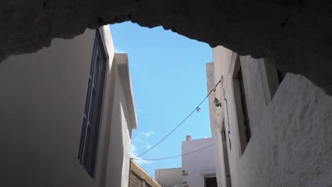 Reveal-of-typical-white-greek-houses-and-sky-behind-arch-SLOW-MOTION