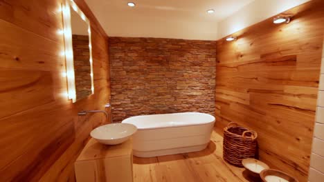 Extreme-wide-shot-of-a-cozy-bathroom-with-wood-flooring-and-an-illuminated-mirror