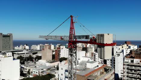 Aerial-view-of-the-city-Montevideo-Uruguay,-with-buildings,-a-crane-building,-the-sea-and-the-clear-sky-in-the-background