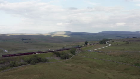 Aerial-Flyaway-Shot-of-the-Flying-Scotsman-60103-Steam-Train-as-it-Passes-Through-Ribblehead-Station-in-North-Yorkshire-with-Wide-Crop
