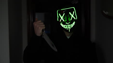 A-terrifying-killer-in-a-generic-halloween-mask-chasing-a-scared-victim-with-a-knife-in-slow-motion
