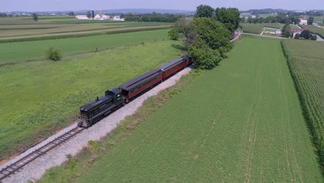 An-Aerial-View-of-a-Diesel-Locomotive-Pulling-Vintage-Passenger-Cars-Through-the-Amish-Countryside