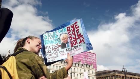 A-young-Scottish-protester-holding-and-looking-at-her-homemade-sign