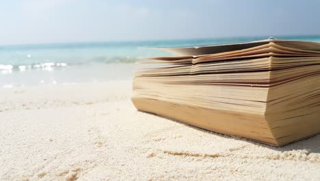 Dickes-Buch-Liegt-Auf-Weißem-Sand-Eines-Exotischen-Strandes-Mit-Verschwommenem-Hintergrund-Aus-Meereswellen,-Kopierraum-Mit-Urlaubsthema