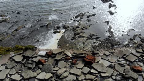 Aerial-view-of-stones-in-the-sea-with-waves-crashing-on-the-pier,-Montevideo,-Uruguay