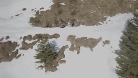 Aerial-drone-selfie-of-a-young-man-alone-sitting-on-the-top-of-the-mountain-with-snow,-looking-at-beautiful-landscape-in-Dolomite-Alps,-Madonna-di-Campiglio,-Cinque-Laghi,-Val-Rendena,-Italy