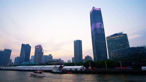 Sightseeing-boat-takes-tourists-on-an-evening-tour-of-Shanghai's-famed-Huangpu-River-showcasing-spectacular-lights-on-nearby-commercial-buildings