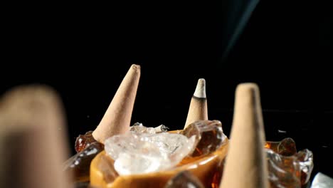 Static-view-of-unlit-incense-cones-in-a-decorative-rock-garden-which-shakes-as-off-camera-hand-is-trying-to-direct-smoke,-finger-pushes-over-lit-cone---smoke-is-more-visible