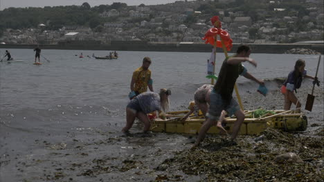 Local-business-Tropical-theme-team-finishing-at-the-Newlyn-raft-race-charity-fun-outdoors-event,-Cornwall