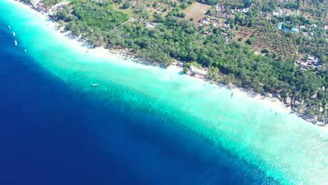 Deep-blue-sea-and-calm-turquoise-lagoon-around-exotic-beach-with-white-sand-of-tropical-island-with-trees-and-plantations-in-Bali