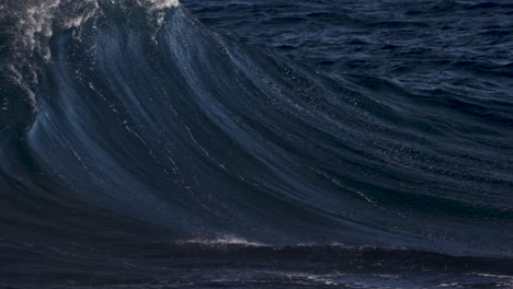 Welle-Bricht-An-Einem-Sonnigen-Tag-In-Zeitlupe,-Während-Gischt-Dank-Eines-Starken-Ablandigen-Windes-Wieder-über-Die-Wellenfläche-Bläst