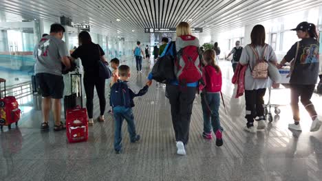 Xian,-China---July-2019-:-Mother-and-her-children-walking-in-the-airport-corridor-after-arriving-by-plane