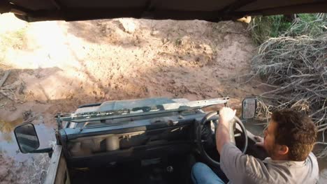 Crossing-a-puddle-in-heavy-offroad-terrain-with-a-safari-4x4-land-rover