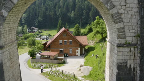 Aerial-push-in-through-railway-viaduct-bridge-with-a-cyclist-passing-beneath-it-in-Slovenia